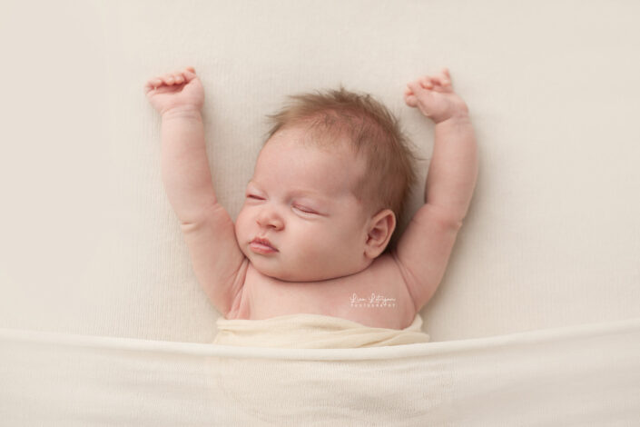 newborn photography studio portrait of baby stretching arms by newborn photographer