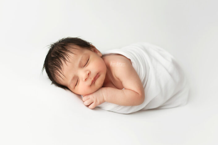newborn photography studio portrait of baby on white blanket by newborn photographer