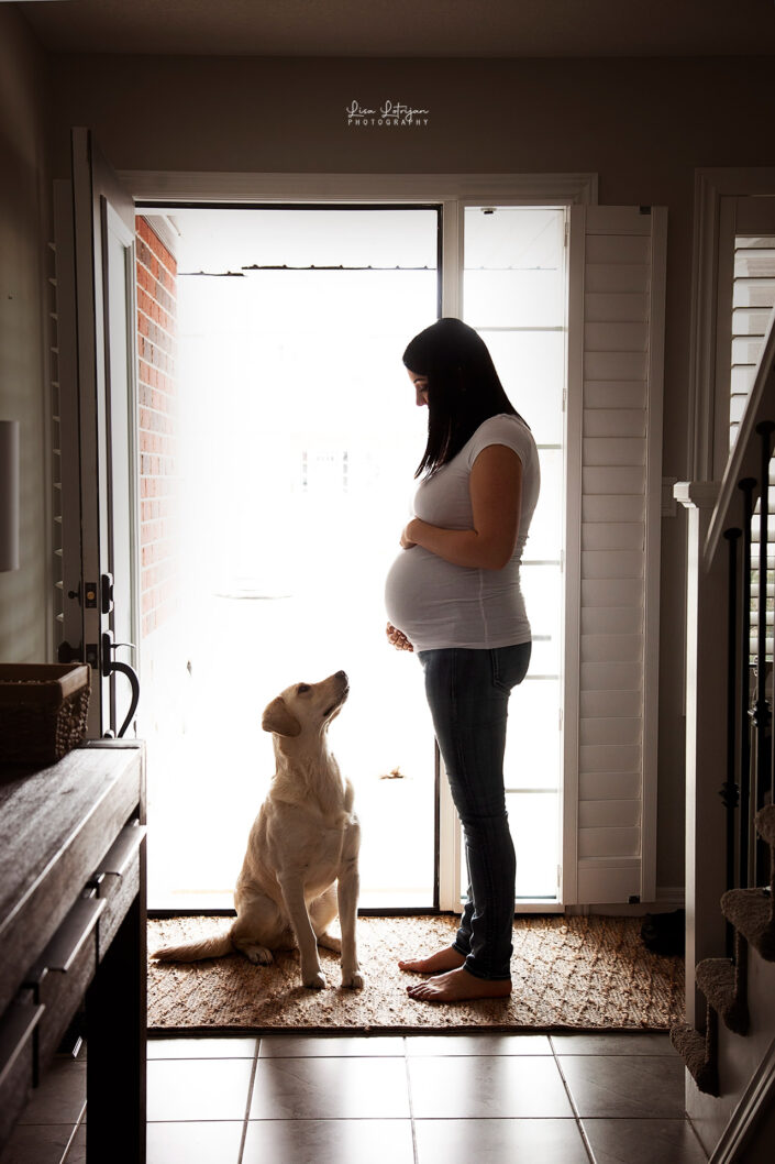 family photography portrait of expecting mother in backlit doorway with pet dog by newborn and family photographer